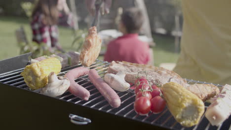 close-up of man standing at barbeque grill and turning over meat