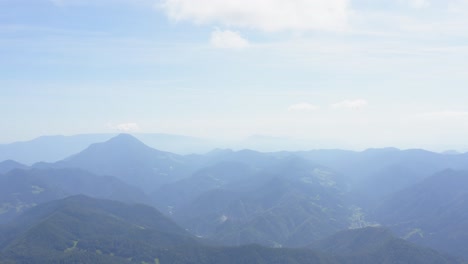 a high-altitude drone shot shows a wide view of the mountain range on a misty day