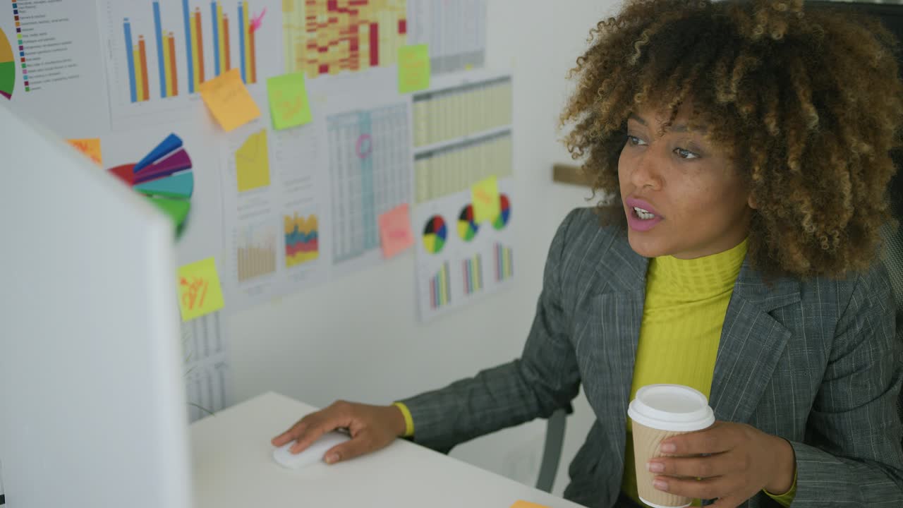 Young worker having coffee while using computer