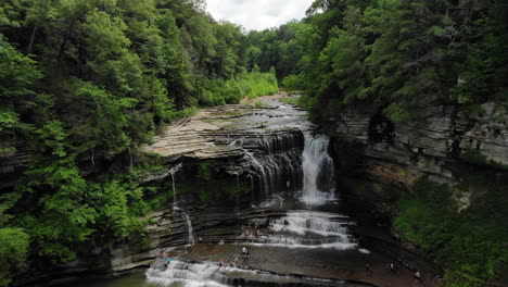 Cummins-Falls-aerial-drone-shot-panning-down-with-waterfalls,-lush-green-forest-and-river-rocks