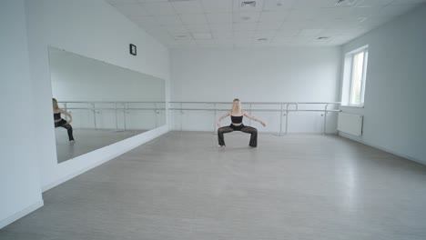 chica en forma con ropa negra actuando contemporáneamente. bailarina muestra movimientos fluidos, cuerpo y manos ondas en la habitación blanca. coreografía de danza de ballet moderno. joven se mueve suavemente