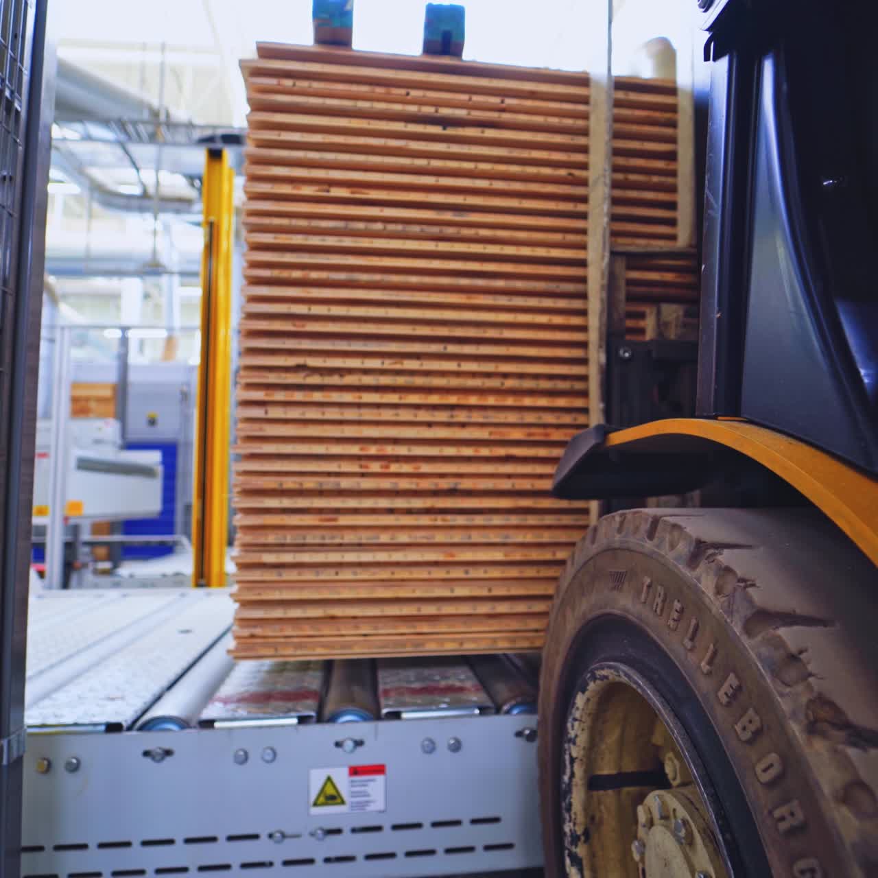 Laminate production. Forklift cart puts the stack of parquet boards on the stand. Interior of a factory of woodworking industry.