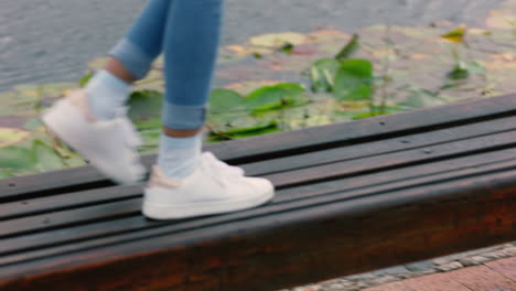 close up woman legs walking in park jumping on benches enjoying playful fun outdoors happy teenage girl wearing white shoes