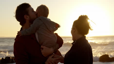 padre y madre jugando con su bebé en la playa 4k