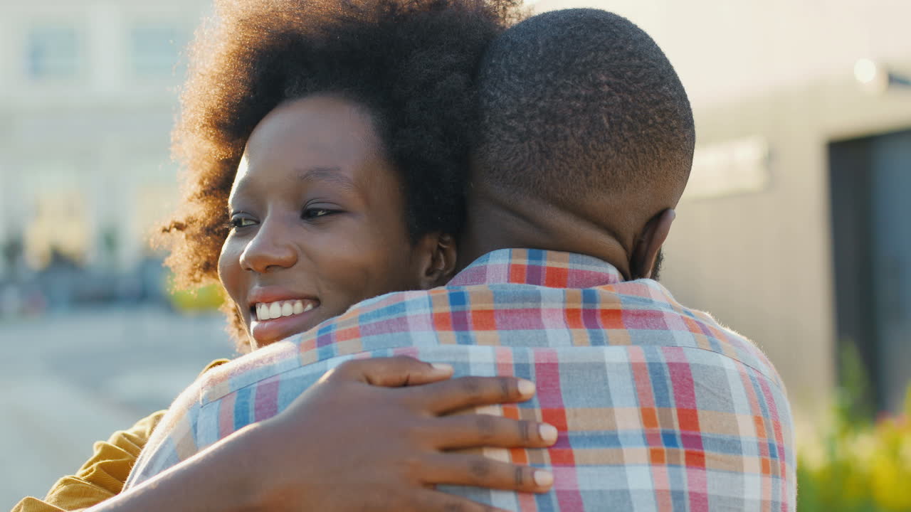 Close-up view of happy african american young couple meeting at train station and hugging on nice summer day