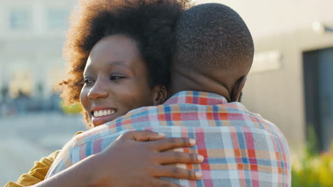 Vista-De-Cerca-De-La-Feliz-Pareja-Afroamericana-Reunida-En-La-Estación-De-Tren-Y-Abrazándose-En-Un-Agradable-Día-De-Verano