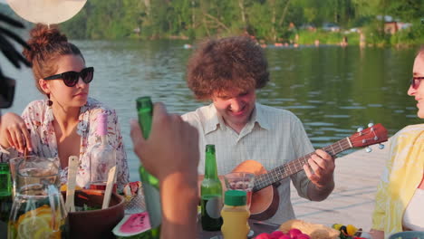 joyous man playing ukulele at summer party with friends