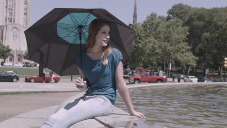 young woman sitting by a fountain on a sunny day