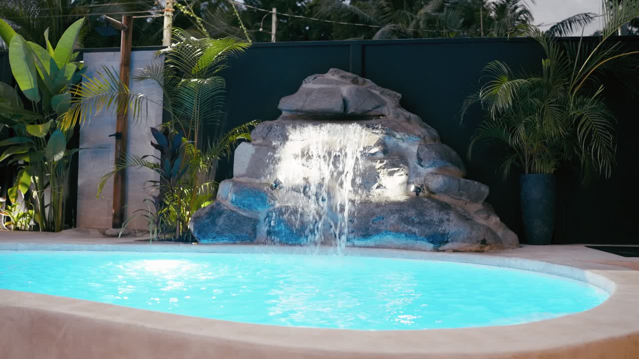 Tropisk swimmingpool med klippevandfald og frodige planter