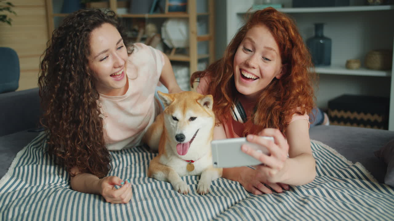 Friends taking a selfie with their dog on the sofa