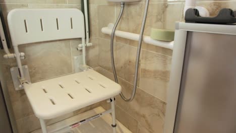 pan shot of foldable disabled seat inside shower area with foldable doors and sponge