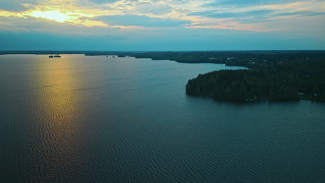 Die-Untergehende-Sonne-Spiegelt-Sich-Auf-Der-Ruhigen-Oberfläche-Eines-Sees-Im-Süden-Finnlands,-Seeufer-Mit-Wald