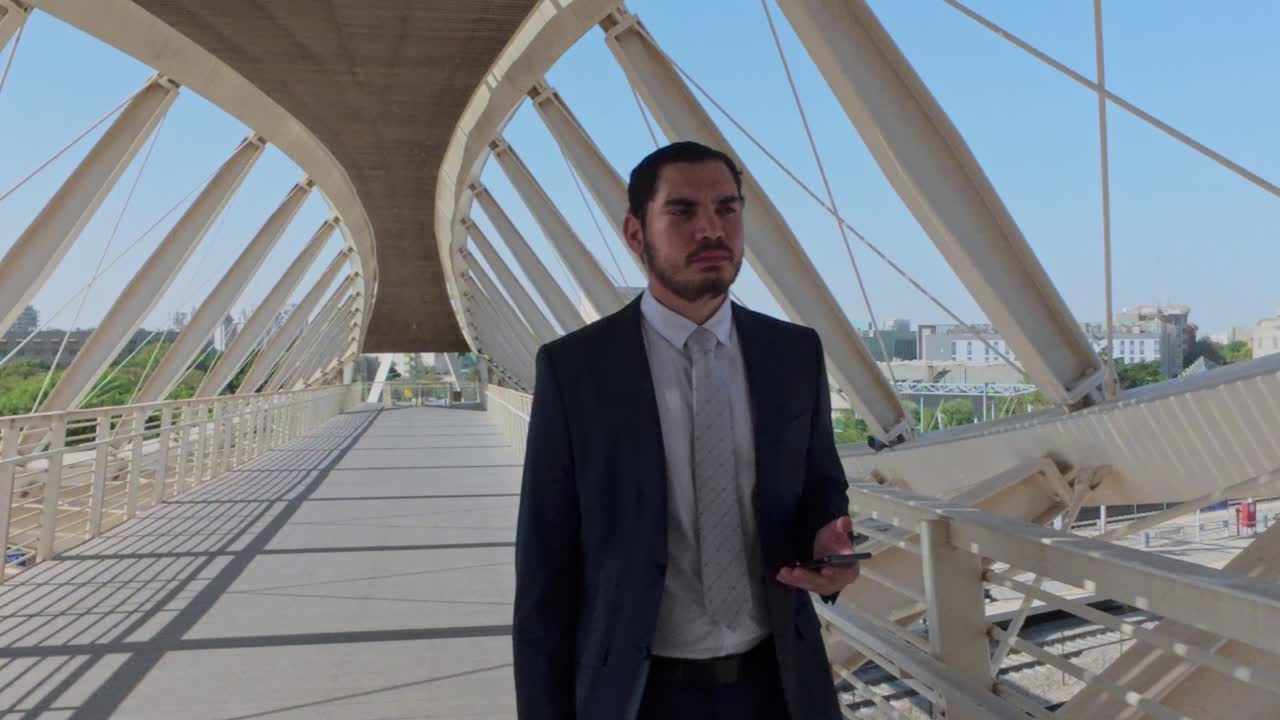 Man in Suit Walking on Bridge with Phone