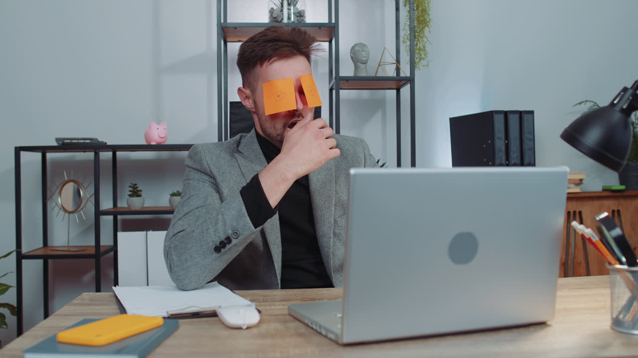 неэффективный усталый ленивый бизнесмен работает спит на ноутбуке с наклейками на глазах на лице