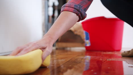 close up of woman at home mopping up water from leaking pipe