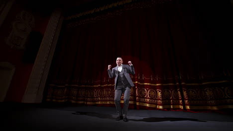 actor in suit on large theater stage. male comedian telling jokes and dancing gestures on the scene. joyful performer on stage.