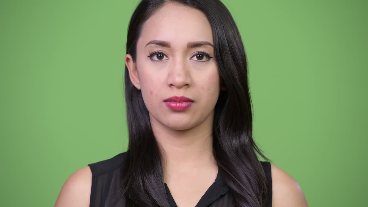 Young beautiful Asian businesswoman against green background