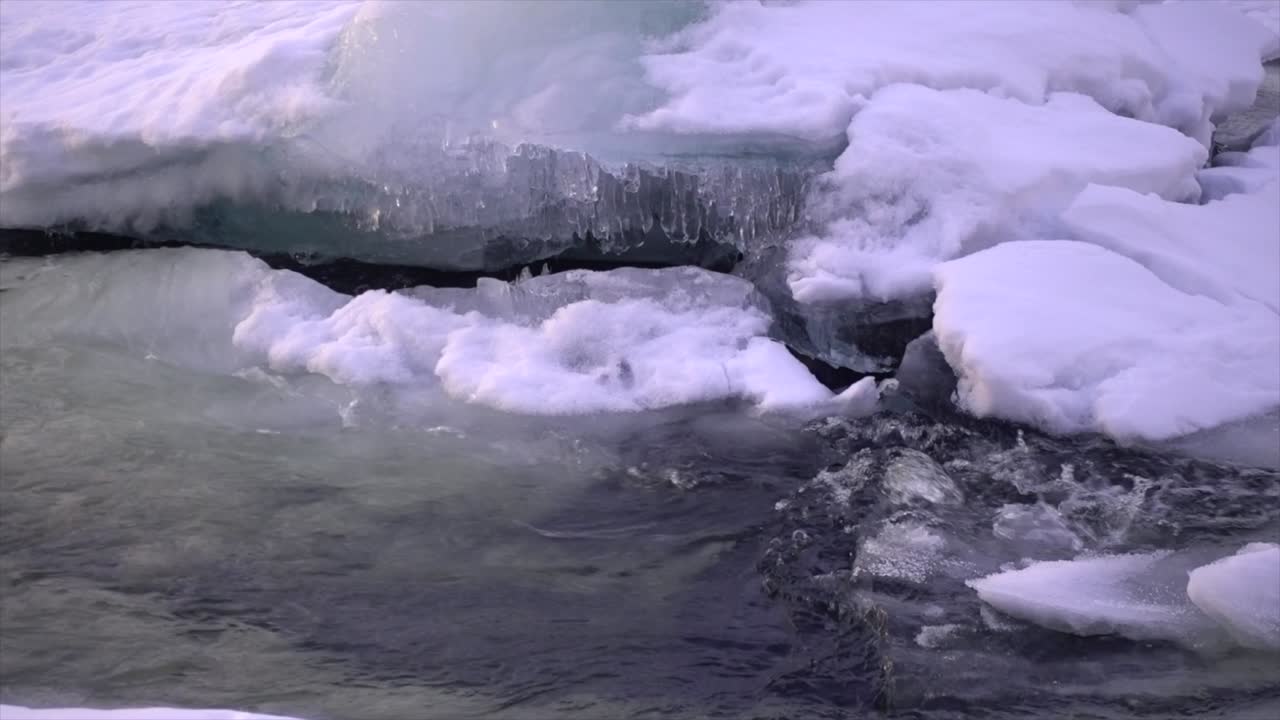 Arctic river melting and flowing down through a forest in the northern polar circle during a stunning yellow and orange coloured sky at sunset.
