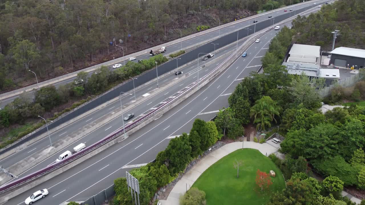 드론이 연못이 있는 식물원 위의 주요 다중 차선 고속도로를 향해 날고 있다