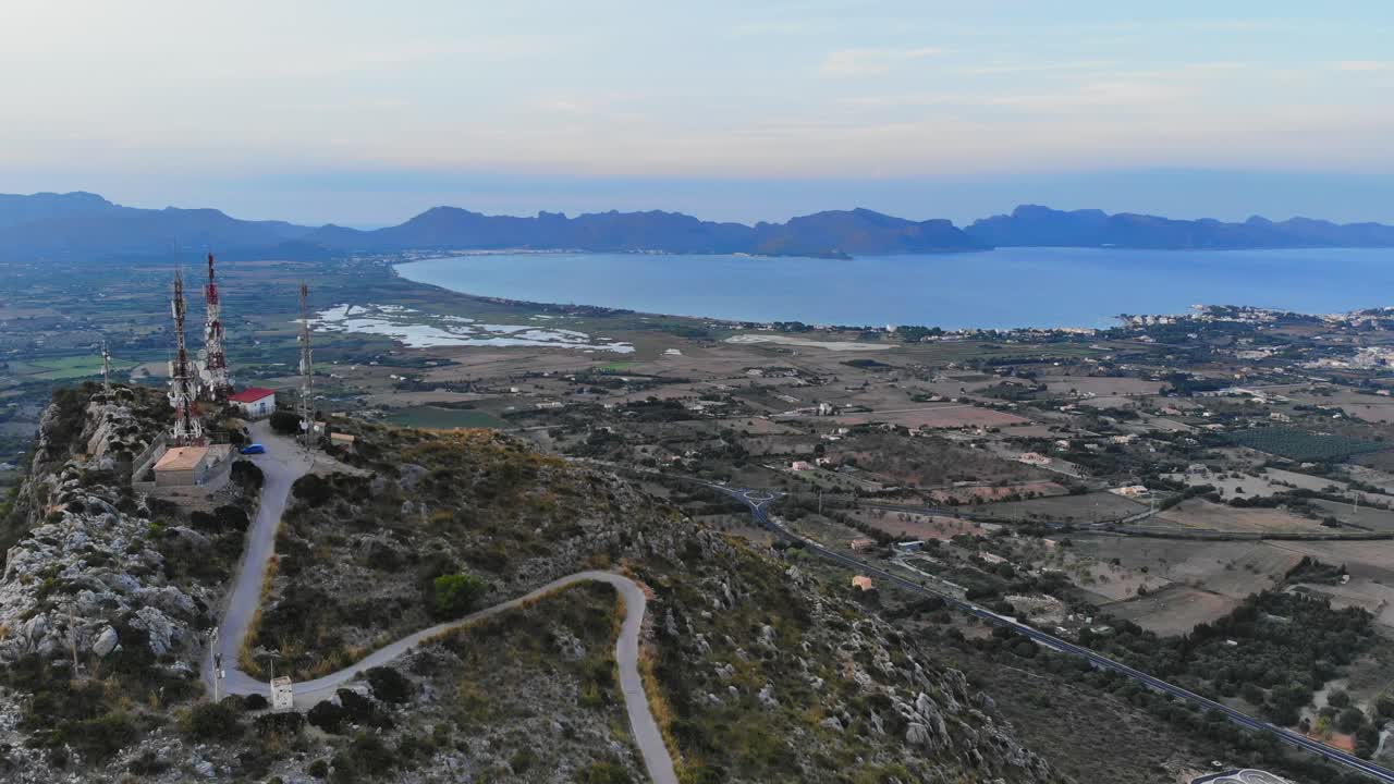 toma aérea de paralaje de antenas en la cima de una colina y la bahía de pollensa en el fondo de mallorca