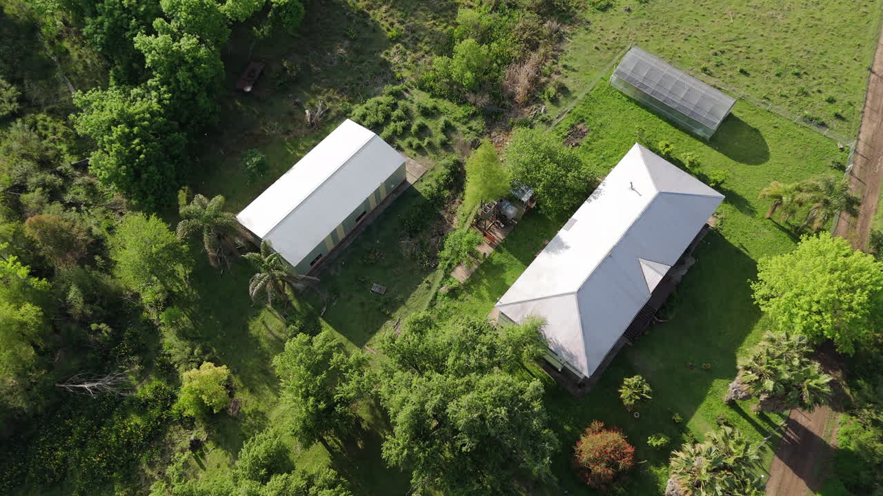 Aerial top-down circular shot of a rural school and cabins nestled in the Argentine Delta, showcasing the surrounding nature