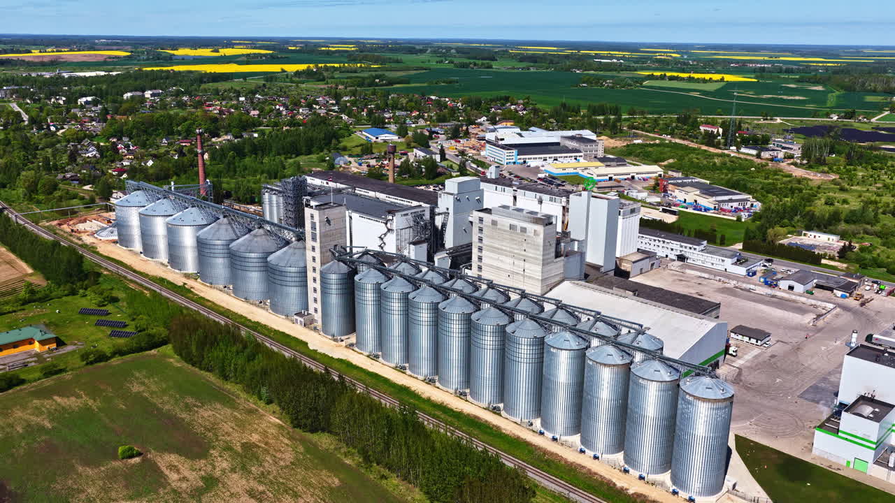 Large grain silos and industrial buildings on a sunny day, aerial view of countryside