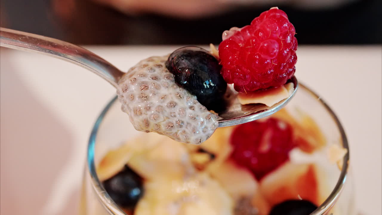 Close up of a woman eating chia pudding with fruit at a cafe