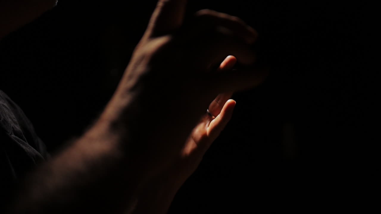 Close-up of a Man's Hands in the Dark