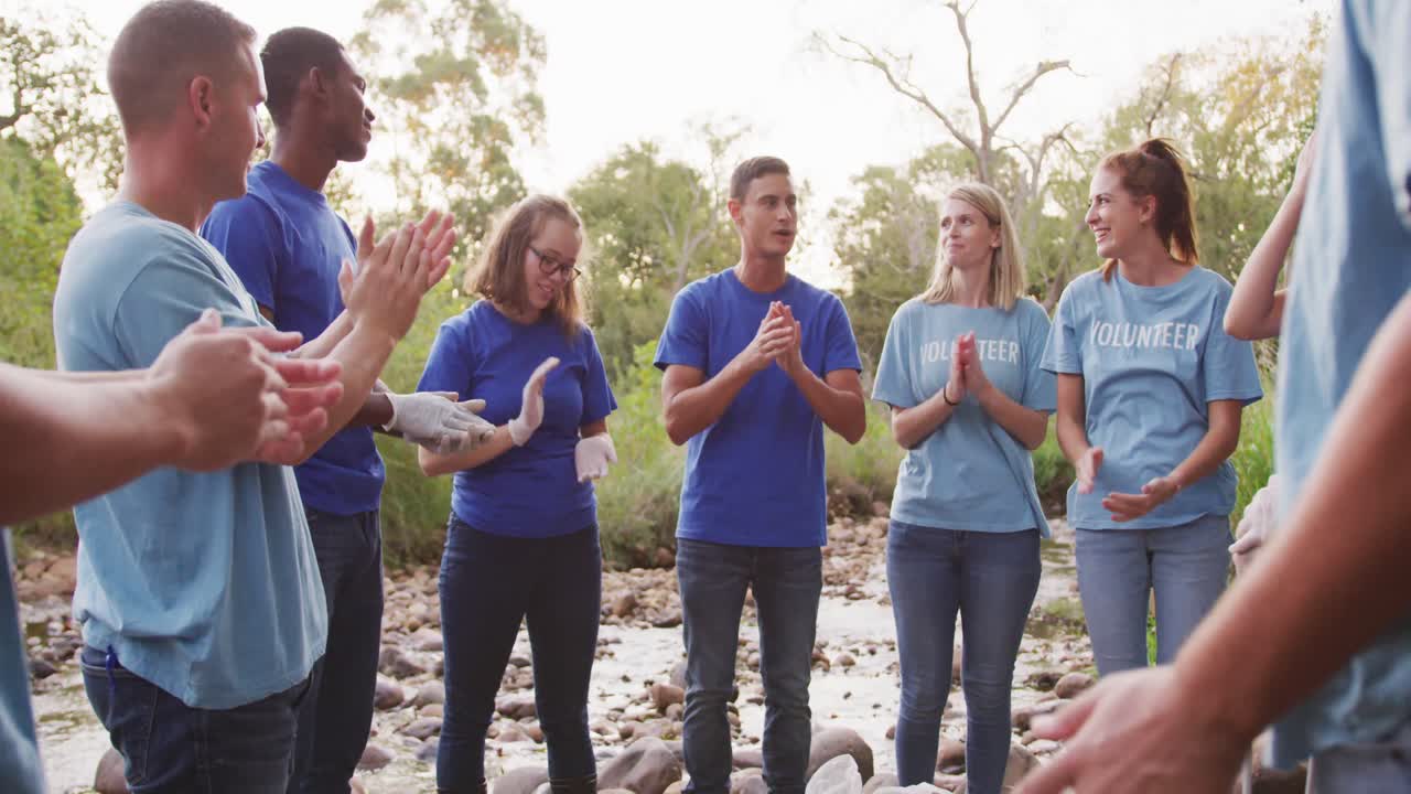 중년 성인 들 이 자원 봉사 하고 강 을 청소 하는 날 에 손 을 박고 있다