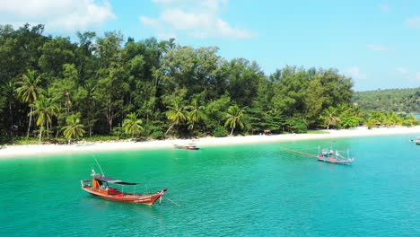 Tranquila-Playa-Exótica-Con-Palmeras-Sobre-Arena-Blanca,-Tranquila-Laguna-Turquesa-Con-Barcos-Anclados-Para-Viajes-Turísticos-En-Tailandia