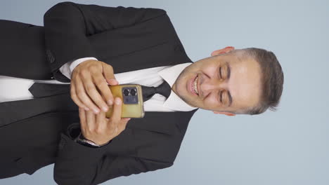 Vertical-video-of-Businessman-texting-on-the-phone.-Happy-emoticon.
