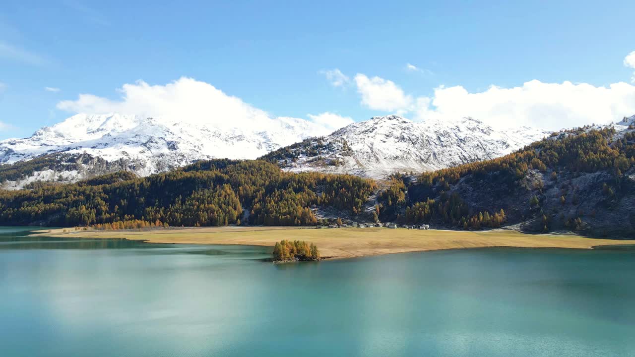 Aerial view of the stunning Lake Sils (Silsersee) Isola in Upper Engadine, Grisons, Switzerlandin Autumn with snowy mountains in the background.