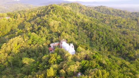 aerial orbviitng shot of chicken church or gereja ayam on rhema hill during sunny day in asia
