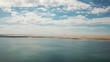 Las-Dunas-Del-Desierto-De-Namib-Y-El-Océano-Atlántico-Se-Encuentran,-La-Costa-De-Los-Esqueletos,-El-Sur-De-áfrica-Namibia,-La-Toma-Aérea-De-La-Isla-De-Los-Tiburones-De-La-Ciudad-De-Luderitz