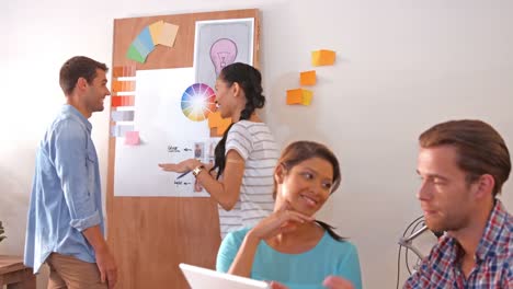 Creative-team-using-laptop-computer-while-their-colleagues-looking-at-color-sample