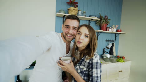 una pareja feliz tomando una selfie en la cocina