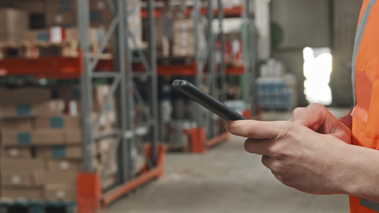 Unrecognizable Warehouse Worker Using Mobile Phone