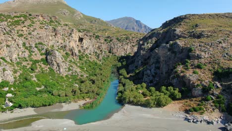 Aerial-dolly-out-of-Kourtaliotis-river-flowing-through-a-gorge-to-the-sea-in-Crete,-Greece