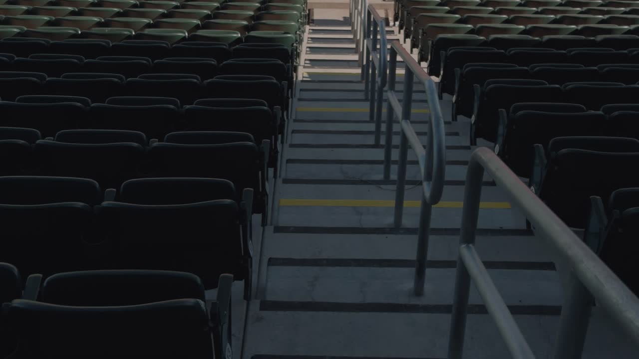 Panoramica lenta e costante che sale dai posti a sedere vuoti dello stadio e dalle ringhiere dei corridoi al campo interno in terra ed erba.