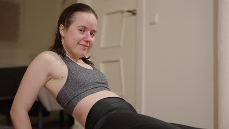 Home-workout,-young-woman-looking-at-the-camera-whilst-holding-stress-positions