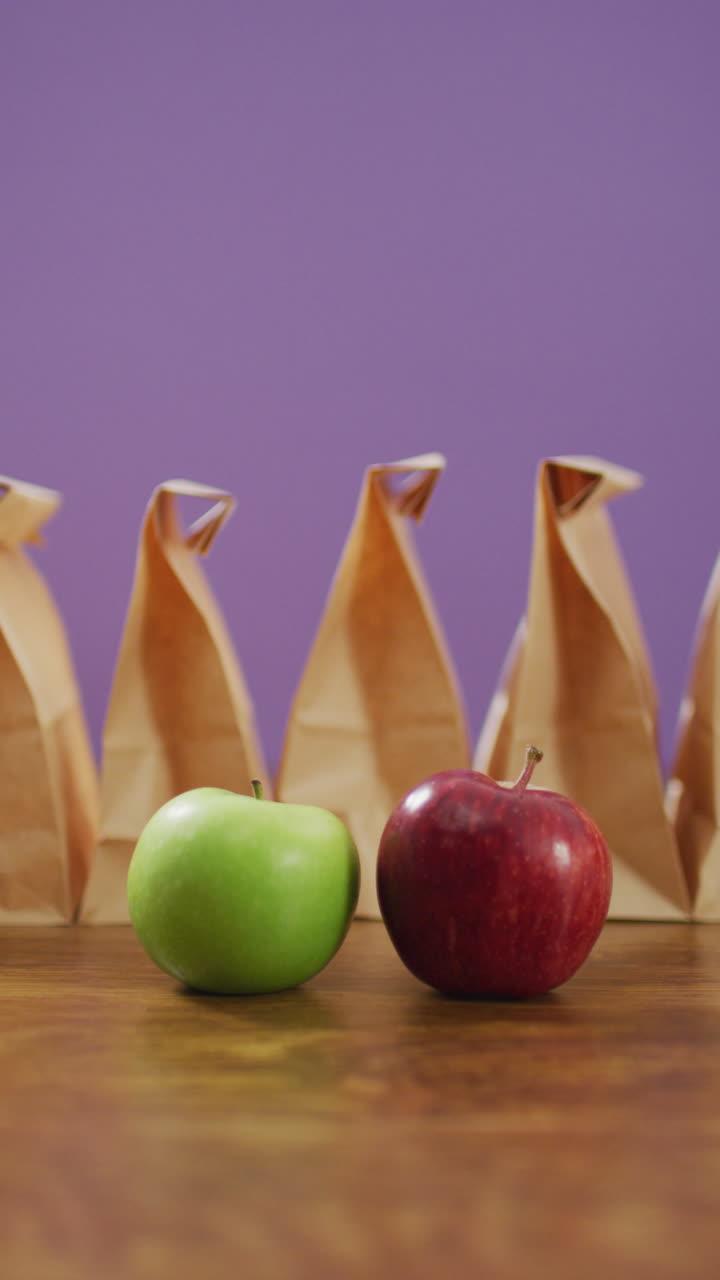 video vertical con manzanas rojas y verdes, almuerzos en bolsas, telón de fondo púrpura