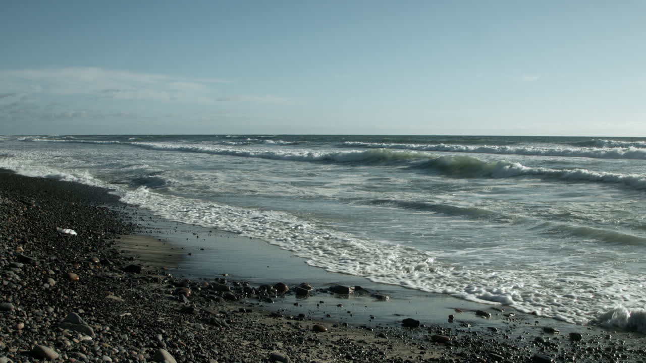 Soft, rhythmic waves gently lap the pebbled shore of Tamarack Beach, their steady motion calming the mind. Under a muted, overcast sky, the tranquil ocean invites deep relaxation and quiet reflection.