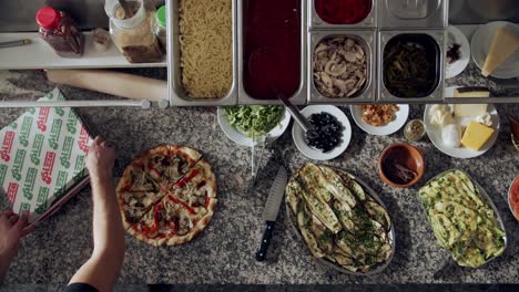 cook preparing pizza for delivery on kitchen