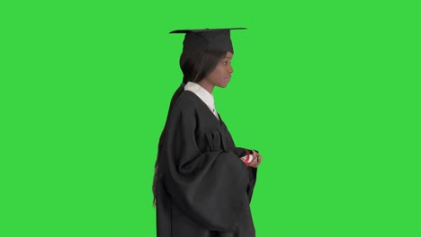 serious african american female graduate walking with diploma on a green screen, chroma key