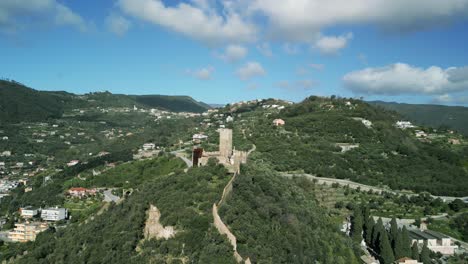 Eine-Malerische-Luftaufnahme-Einer-Alten-Burg-Inmitten-üppiger-Grüner-Hügel,-Die-Einen-Einblick-In-Die-Historische-Architektur-Inmitten-Der-Natur-Bietet