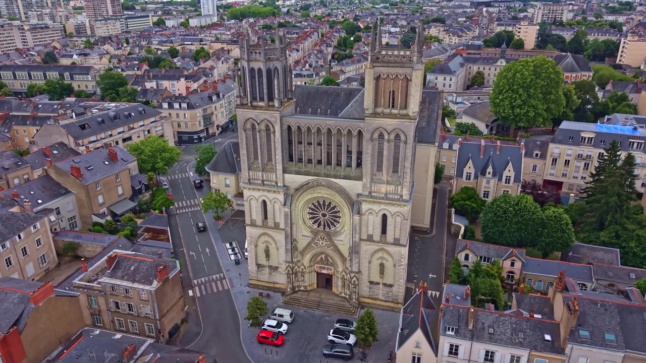Drone che si alza verticalmente sopra la Chiesa di Saint Joseph, rivelando la sua facciata neogotica e la città circostante di Angers