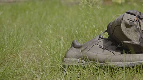 Wide-dolly-of-a-pair-of-discarded-hiking-shoes-lying-in-a-grass-field-on-a-sunny-day