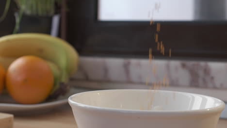 pouring cereals into a white bowl in the kitchen - extreme slow motion