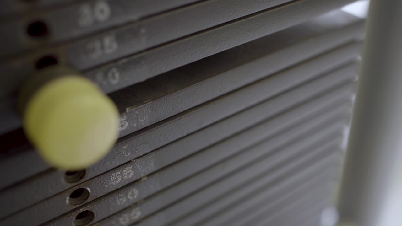 체육관 기계의 무게를 설정하기 위해 핀을 누르는 손을 닫습니다.