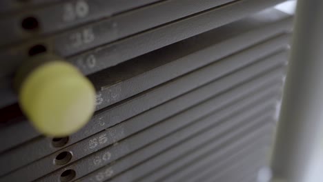 primer plano de una mano empujando el pasador para establecer el peso de la máquina de gimnasio